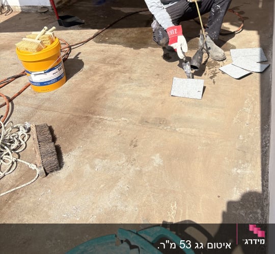 אדם עובד על איטום רצפה עם כלים וחומרים